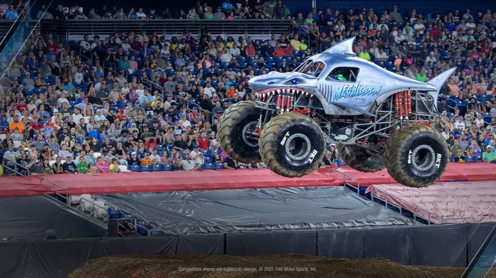 A monster truck soars above a cheering crowd during a motorsport event.
